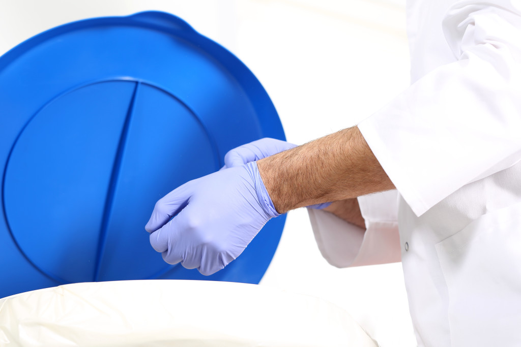 Medical waste, surgeon dropping the gloves in a special container for waste